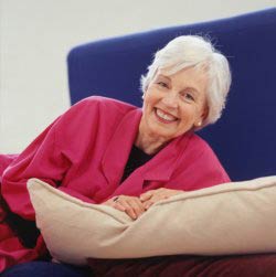 A senior citizen on a sofa smiling