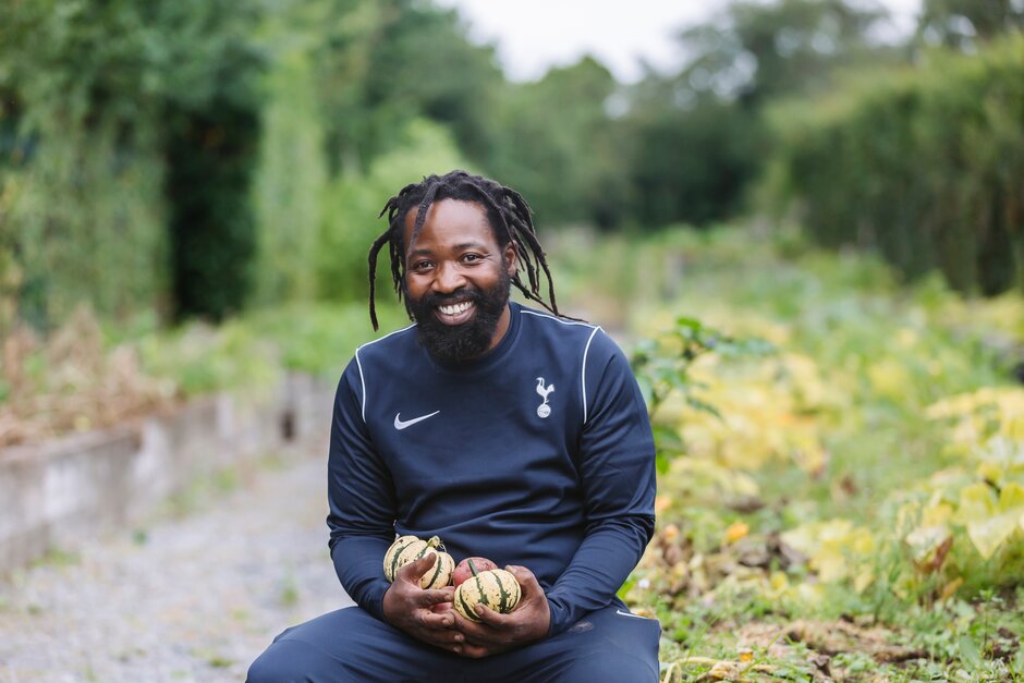 Kuda Chimbudzi holding harvested vegetables in the Tottenham Hotspur Kitchen Garden