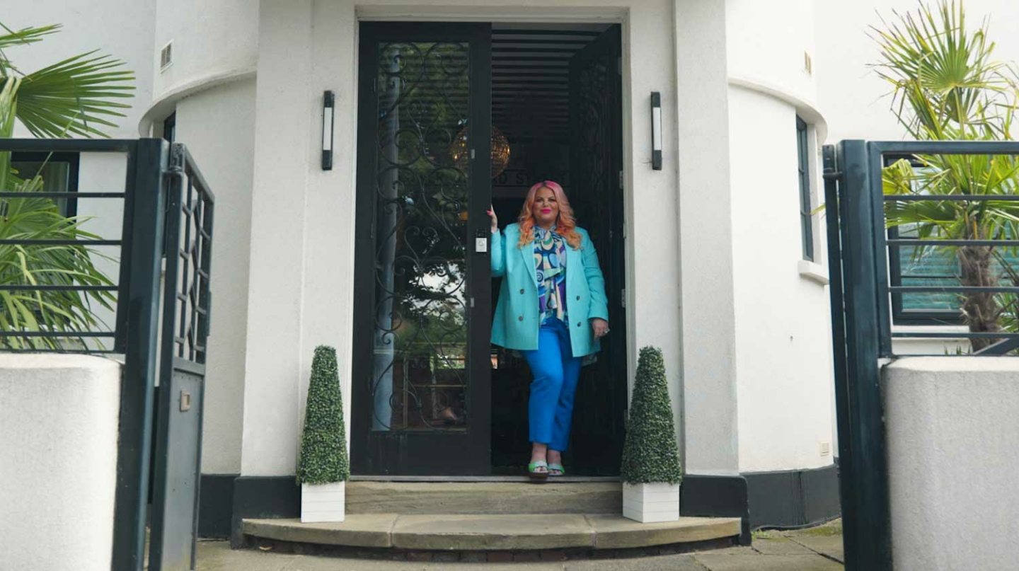 A person stood in the doorway of an Art Deco house