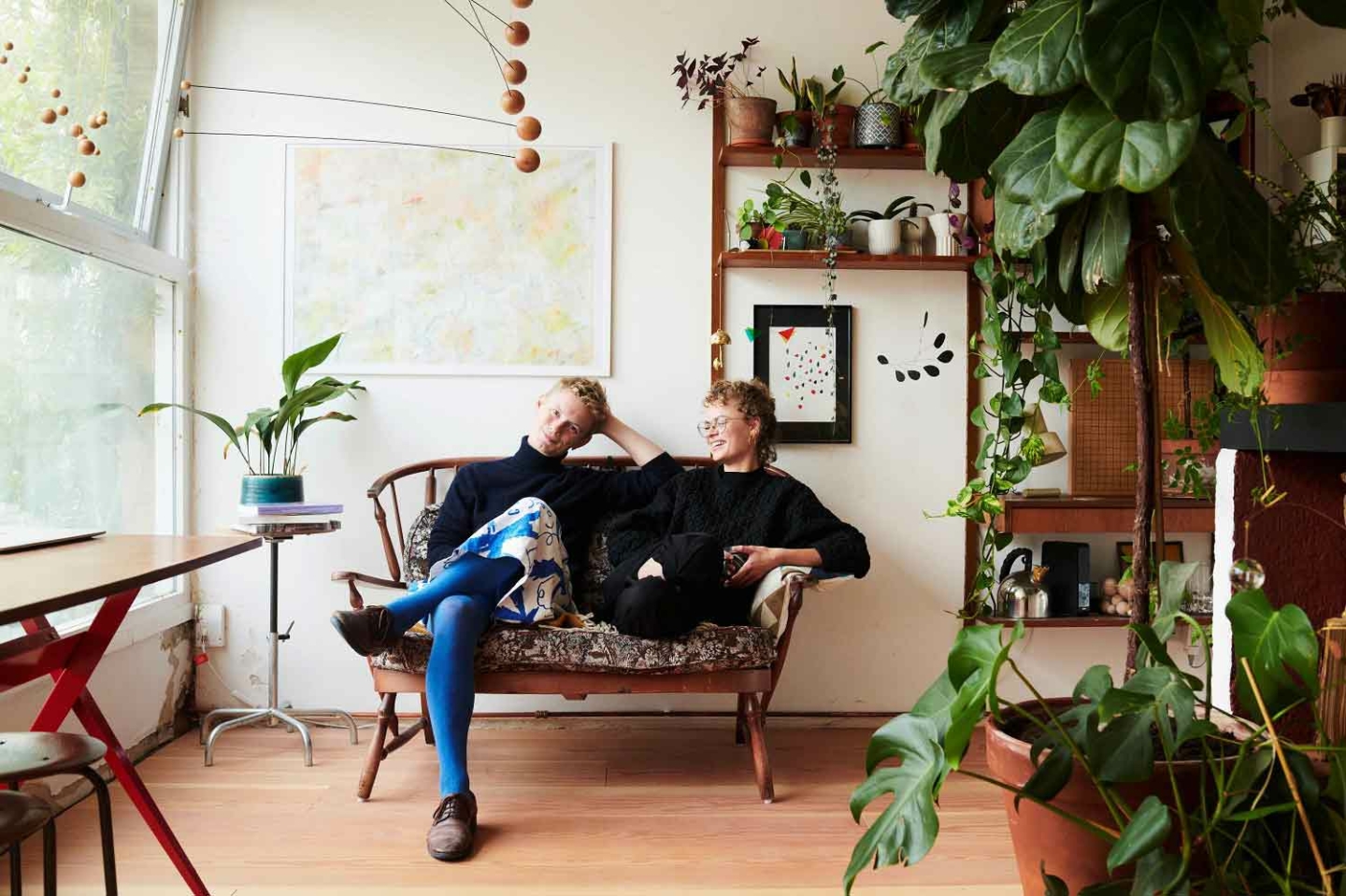 Two people sat on a sofa in a lounge, surrounded by plants