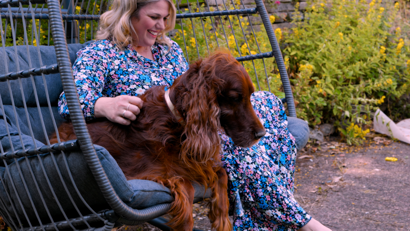 A person and a dog on a swing seat in a garden