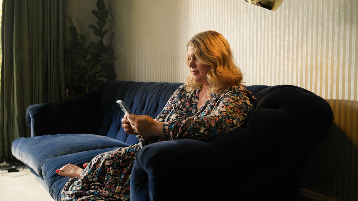 A person on a phone on a navy blue sofa