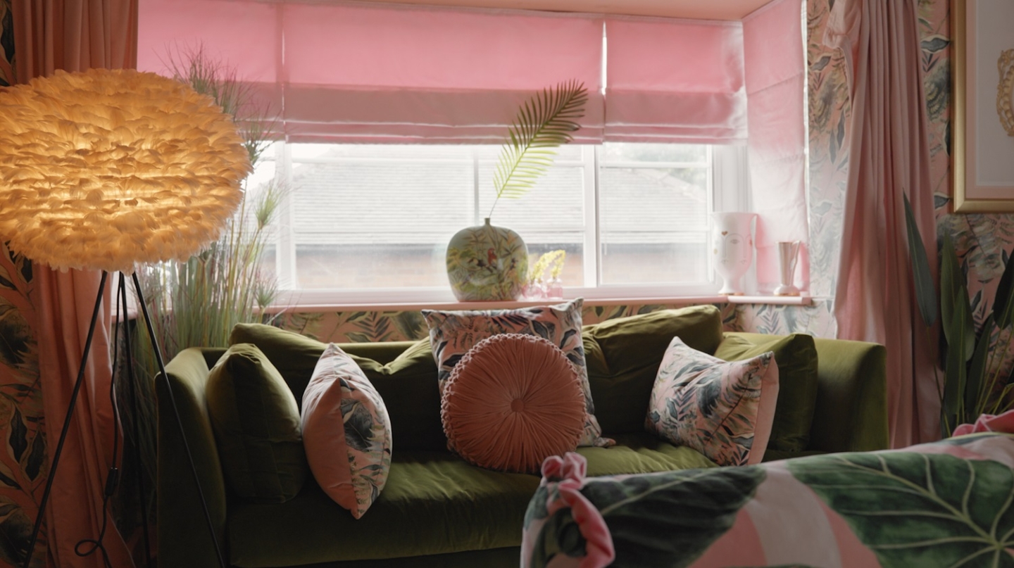 A green velvet sofa with a window in the background