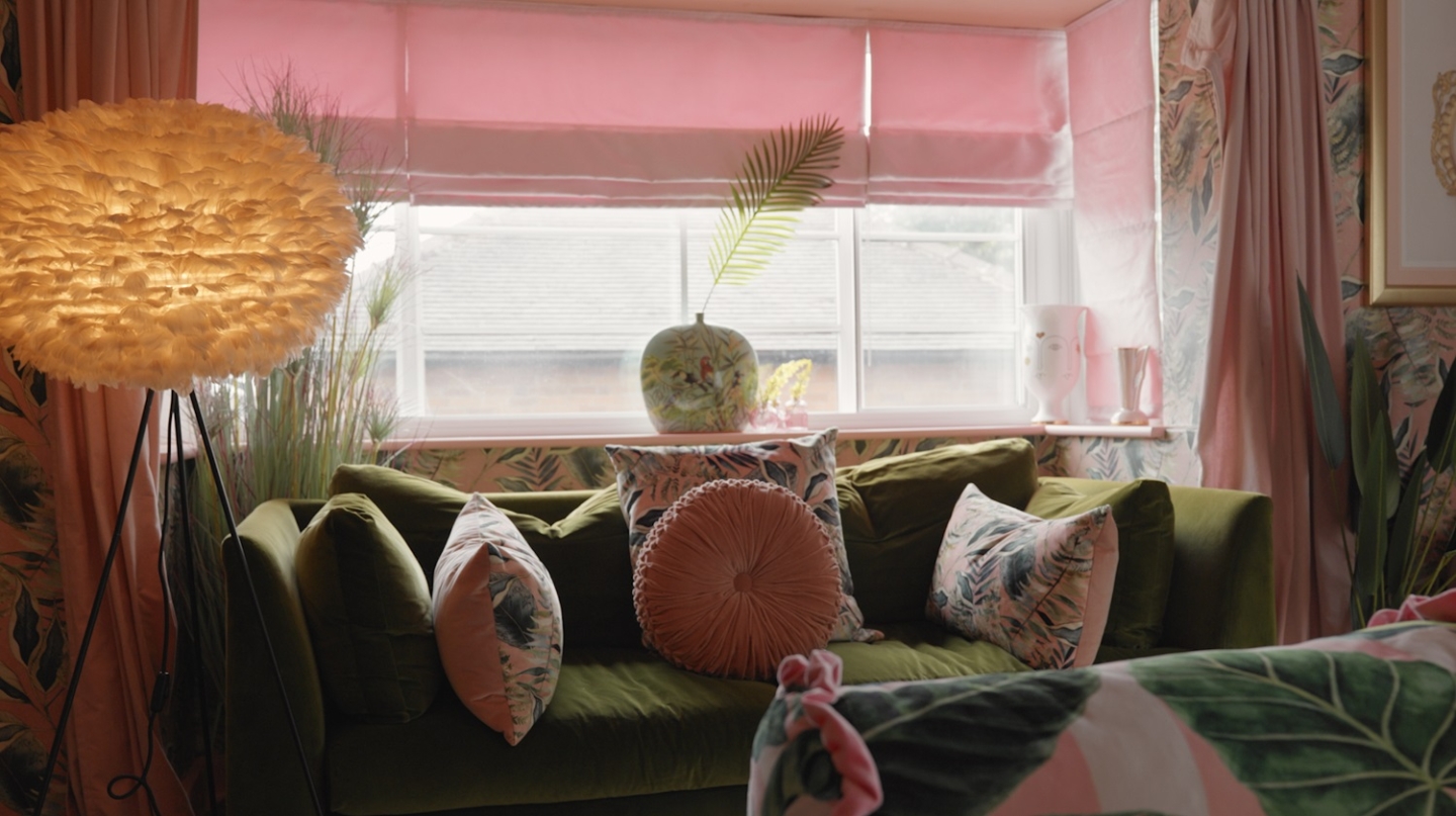 A green velvet sofa with a window in the background