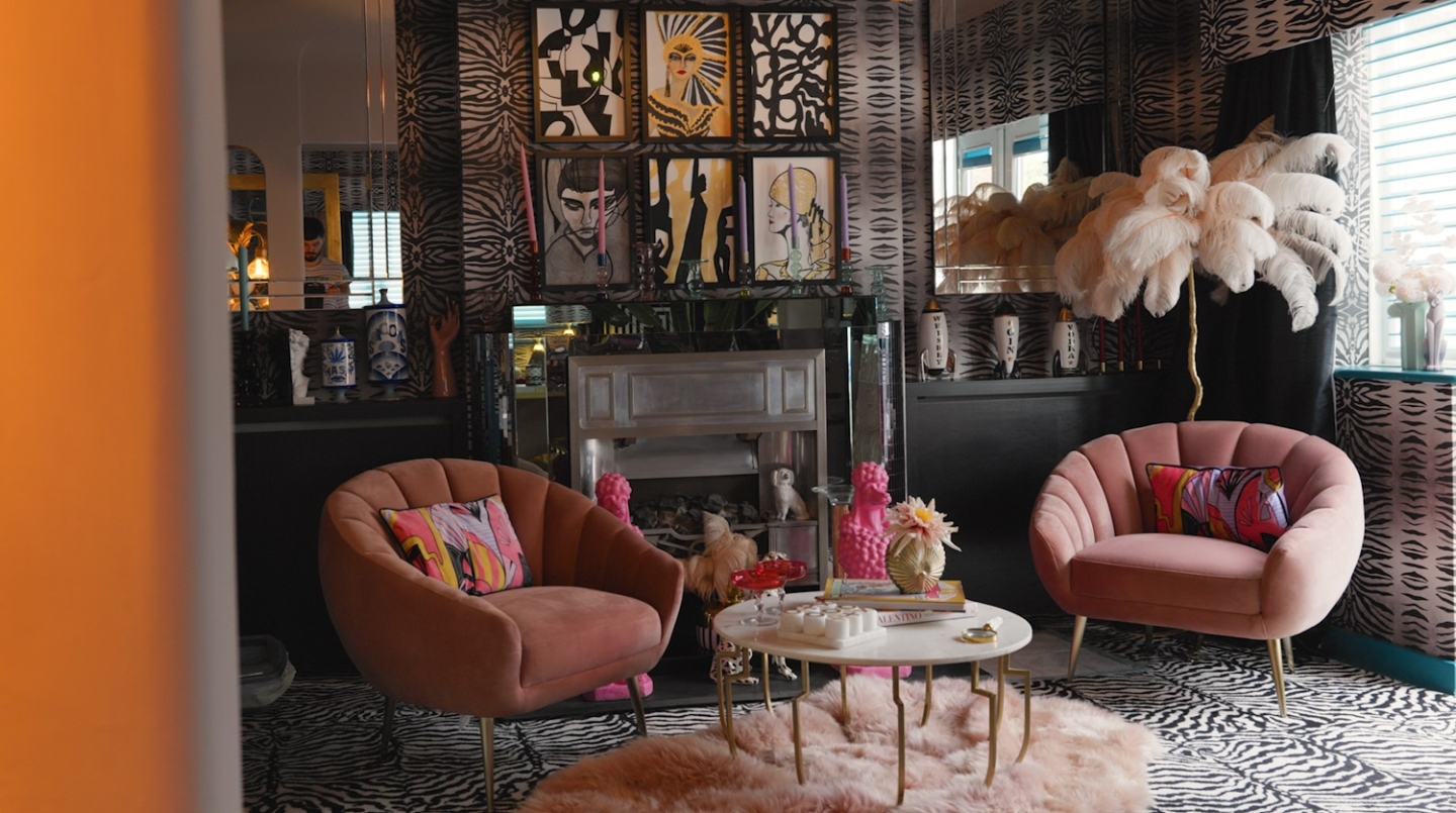 Pastel pink velvet chairs with a fireplace and artwork in the background