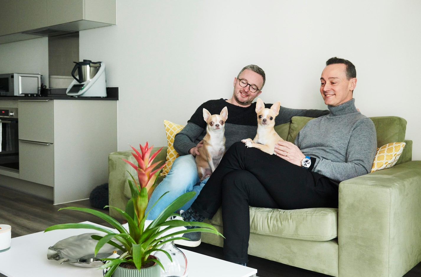 Two people and two dogs on a green sofa