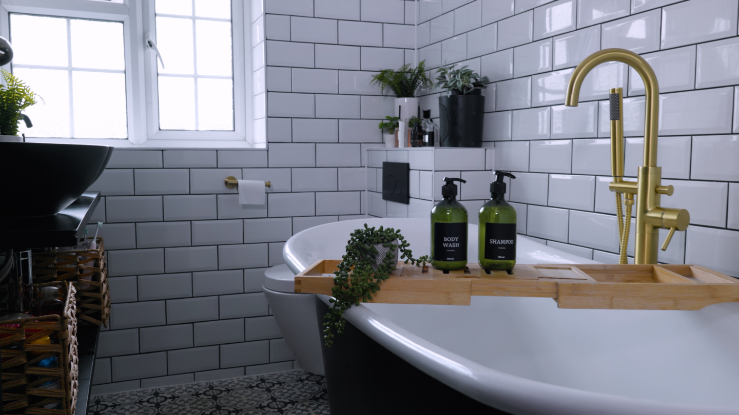 A metro-tiled bathroom with a bathtub and toiletries