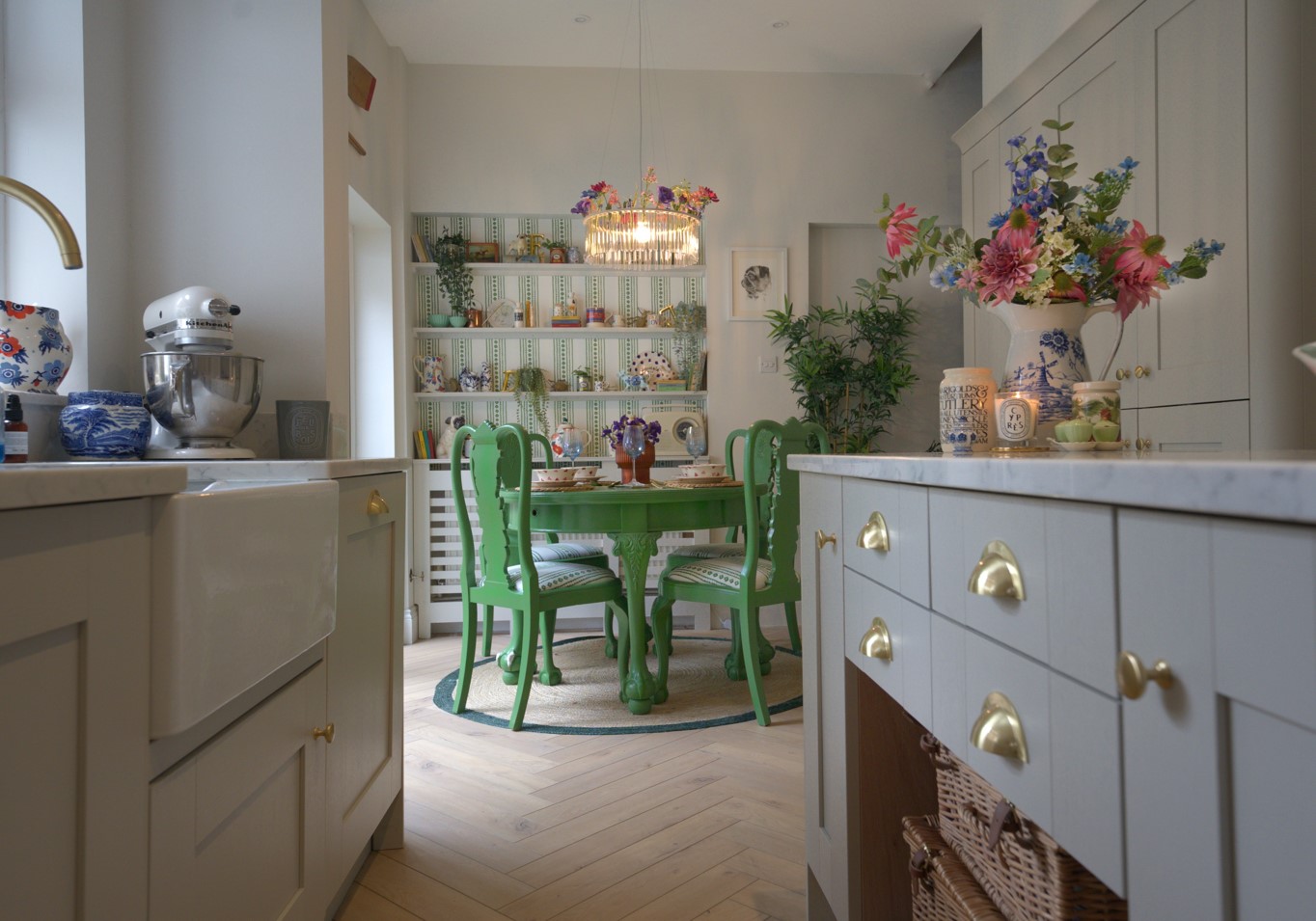 A kitchen with a green dining table, chairs and ornaments