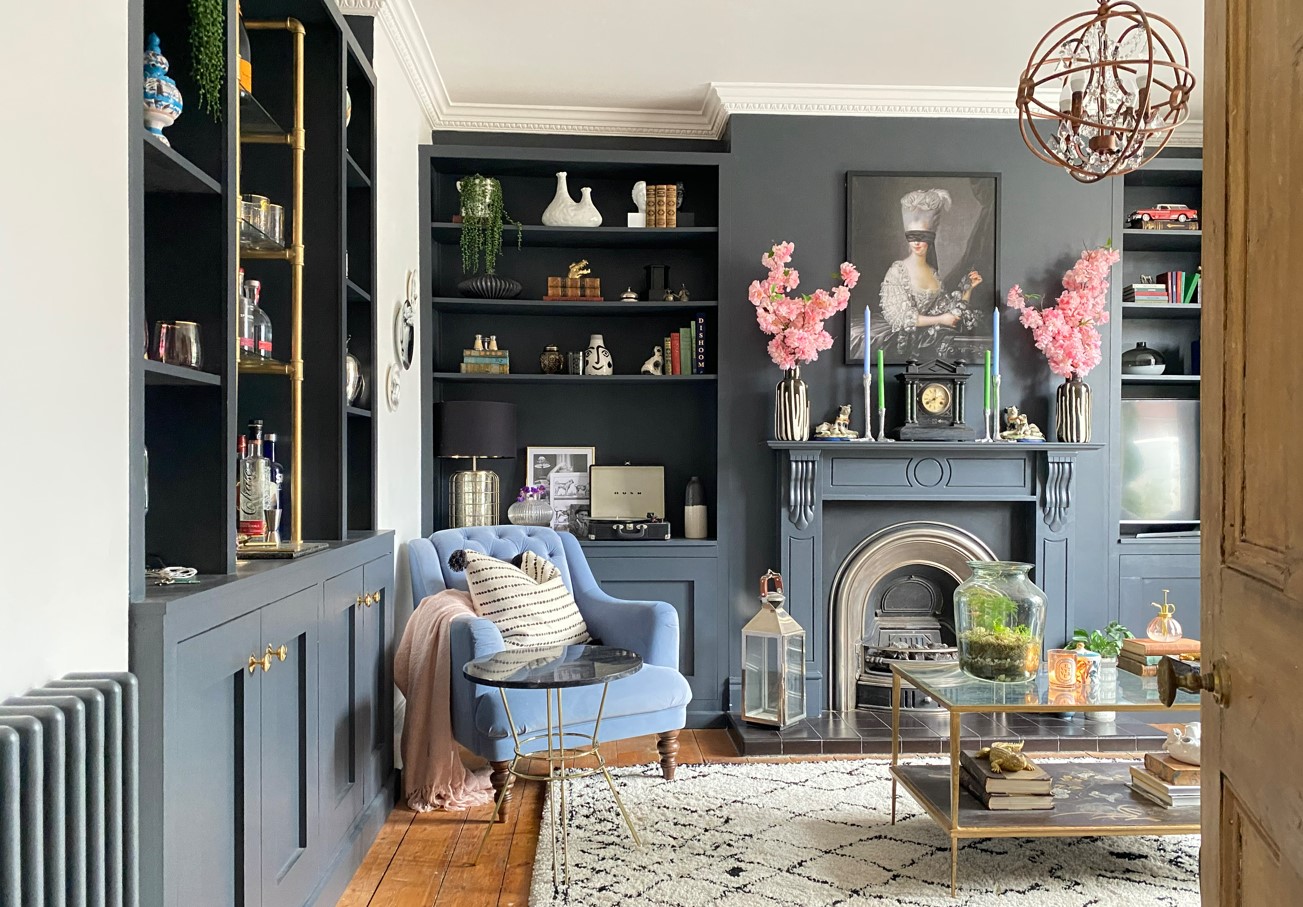 A dark grey lounge, rug, floorboards, armchair and fireplace
