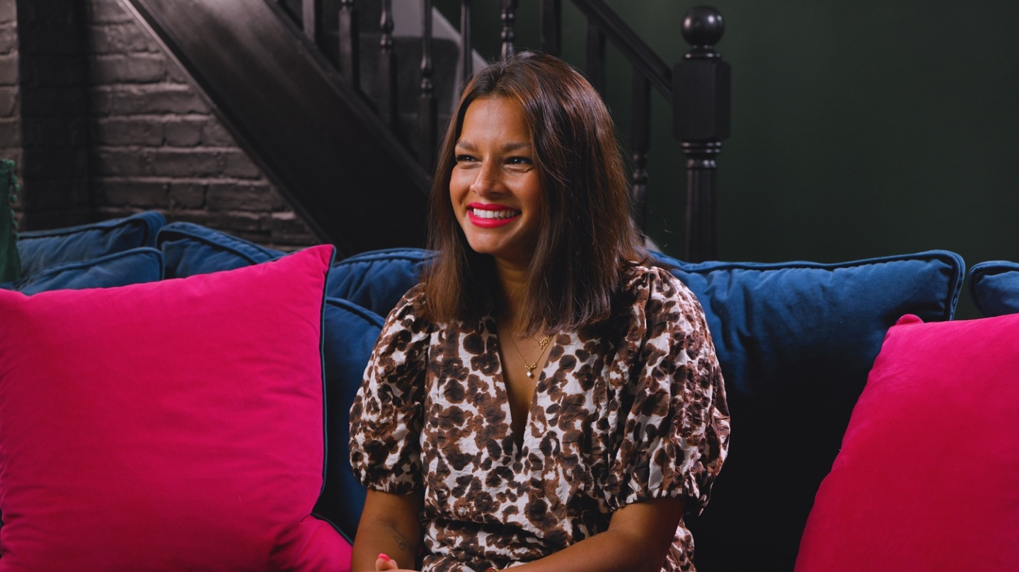 A person sitting on a blue sofa surrounded by pink cushions