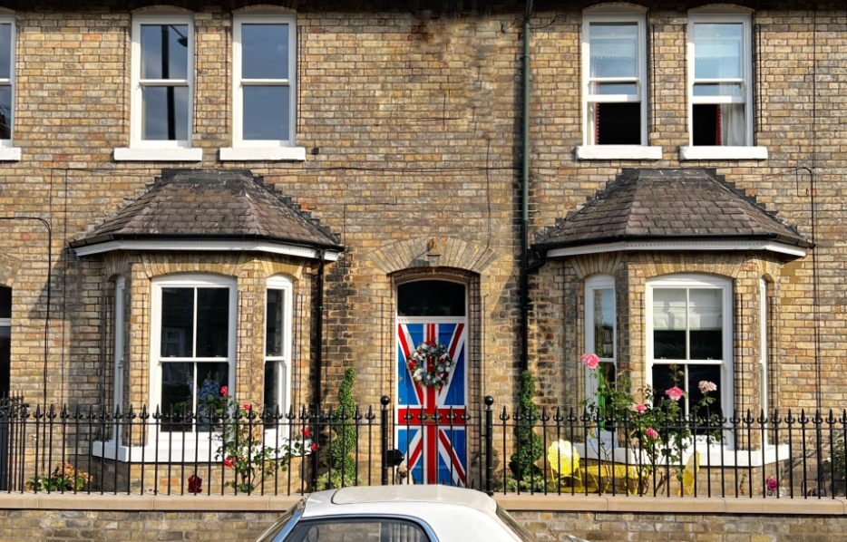 A double-fronted terraced house with iron railings, bay windows 