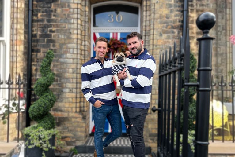 Two people stood outside a front door holding a dog