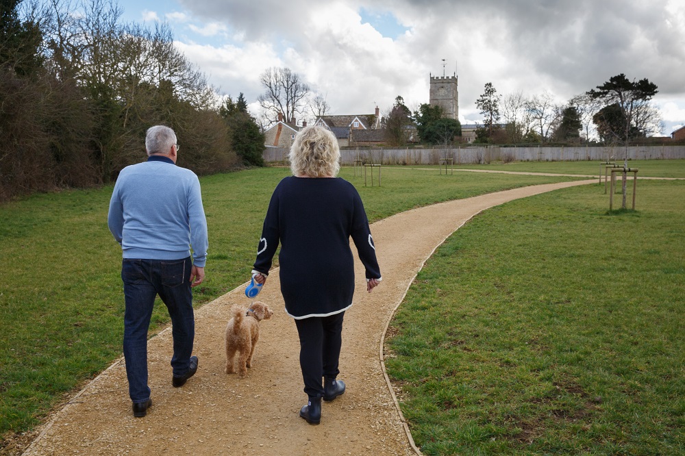 Two people walking a dog in a park