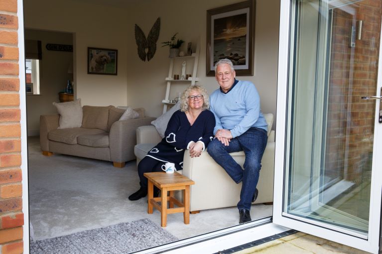 Two people sitting on a sofa next to some patio doors
