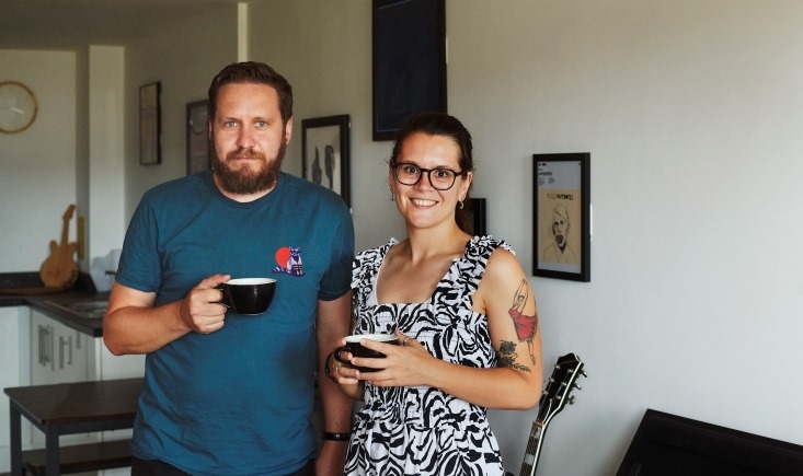 Two people standing with coffee cups in a living room