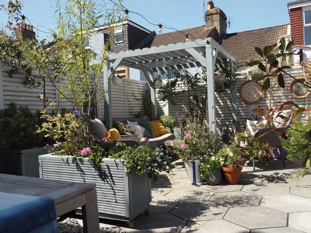 A paved garden with potted plants and a pergola