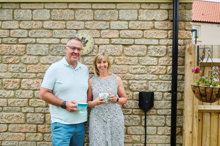 Two people standing by an EV charger
