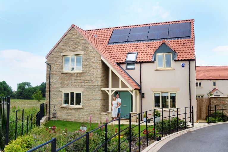 Two people stood outside a house with solar panels