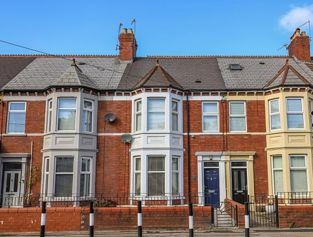 A row of terraced red brick houses with bay windows