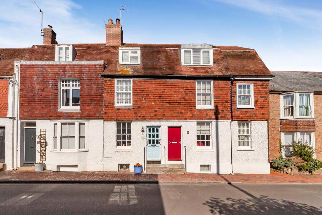 A row of terraced houses with tiled fronts and coloured front doors