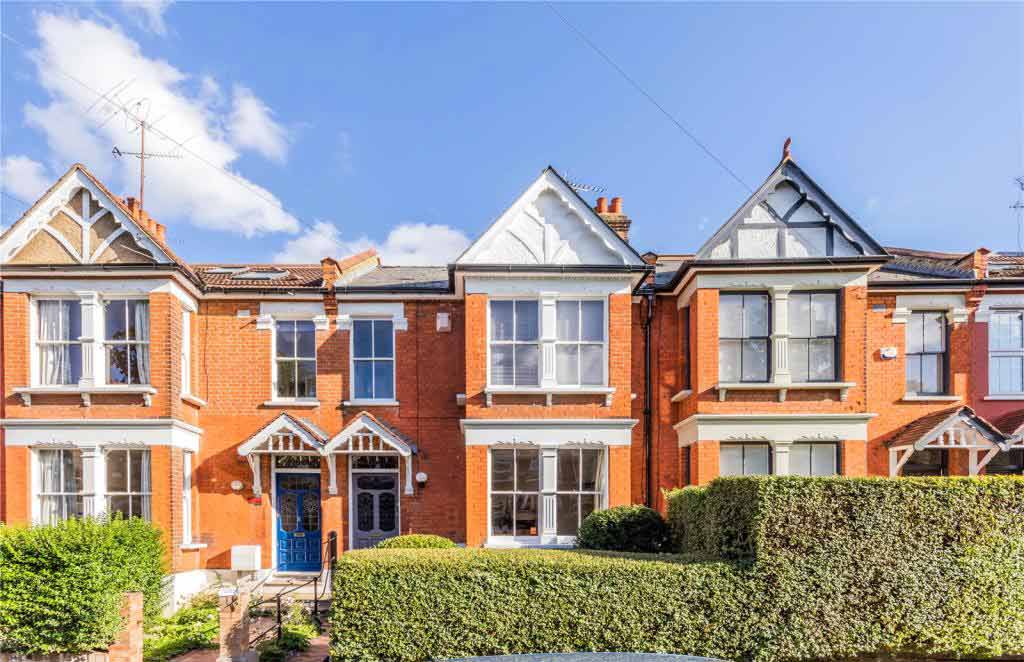 A row or terraced red brick houses, hedgerows and blue sky