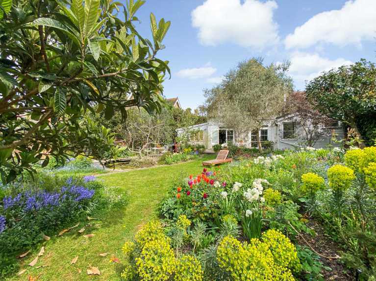 A garden filled with in-bloom flowers and a sun lounger