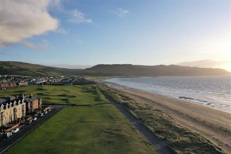 A view of the shoreline in Girvan, grass and a row of houses