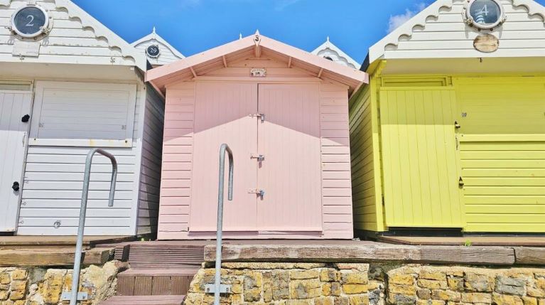 A pink beach hut at the top of some stairs