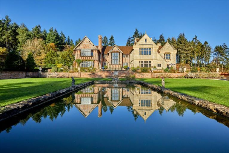 An Arts and Crafts house, reflected in a pond