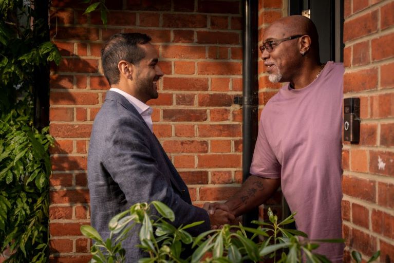 Two people shaking hands in a doorway