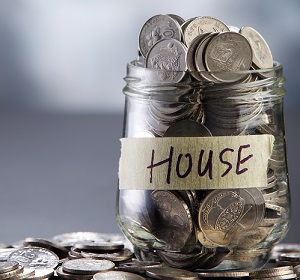 Glass jar labeled house filled with coins.